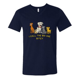 May include: Navy blue V-neck t-shirt featuring a cartoon illustration of five dogs. The dogs are in various colors and breeds. The text "I CALL THE BIG ONE BITEY" is printed below the dogs. The shirt is made of a soft material.