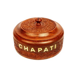 Könnte beinhalten: Ein runder, dunkelbrauner Holzbehälter mit passendem Deckel, der eine aufwendige Blumenschnitzerei aufweist. Die Seite des Behälters zeigt das Wort CHAPATI in hellen, eingelegten Großbuchstaben, umgeben von einer detaillierten floralen Bordüre.