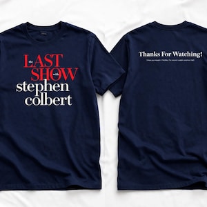 May include: Navy blue t-shirt featuring the text "The Last Show with Stephen Colbert" in red and white on the front. The back of the shirt displays "Thanks For Watching!" in white text. A crew neck, short-sleeved tee.