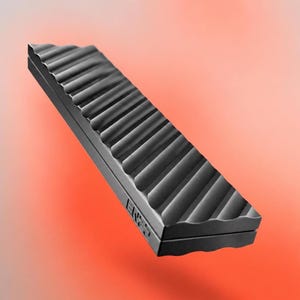 Puede incluir: Un objeto rectangular negro con un patrón acanalado en forma de onda en la superficie superior. El objeto parece estar hecho de un material mate y tiene las letras "EN2S" impresas en un extremo. El fondo es un degradado de naranja y rojo.