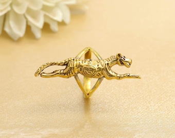 May include: A gold-coloured ring featuring a detailed, running tiger design. The ring's band is a diamond shape, and the tiger is sculpted with intricate details. The ring is set against a soft, golden background.