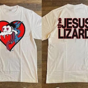 May include: White t-shirt featuring a cartoon wolf inside a red heart on the front. The wolf has a blue and white fur, a long pink tongue, and heart-shaped eyes. The back of the shirt has the text "the JESUS LIZARD" in black and red.