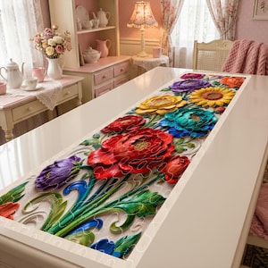 May include: A floral table runner with a 3D effect, featuring vibrant red, purple, yellow, and blue flowers. The runner is placed on a white table, creating a striking contrast. The design includes detailed leaves and stems.