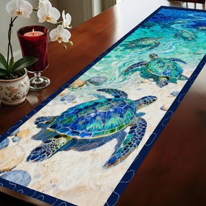 Puede incluir: Un camino de mesa rectangular con un diseño de tortugas marinas. El camino de mesa muestra varias tortugas en tonos azules y verdes, sobre un fondo de playa arenosa y océano. Los bordes están bordeados con un ribete azul oscuro.