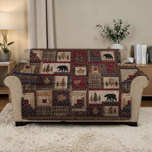 May include: A quilted sofa cover with a rustic design. The cover features a patchwork pattern with squares of various colors and designs, including bears, trees, and leaves. The color palette includes shades of brown, red, and green.