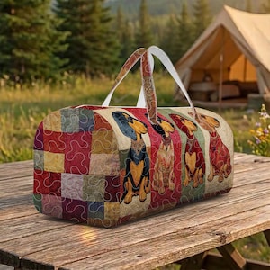 May include: A colorful duffel bag featuring a patchwork design on one side and a row of dachshund illustrations on the other. The bag has white handles and is set on a wooden picnic table. The background includes a tent and trees.
