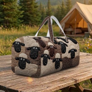 May include: A rectangular duffel bag with a quilted pattern featuring sheep. The bag has a brown and beige color scheme with black sheep designs. It has two brown handles and a white strap for carrying.