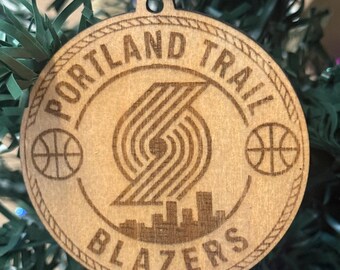 Könnte beinhalten: Weihnachtsornament aus Holz der Portland Trail Blazers. Das Ornament zeigt das Teamlogo, die Worte "PORTLAND TRAIL BLAZERS" und den Namen "DAVID". Das Ornament ist rund und hat ein silbernes Band zum Aufhängen.