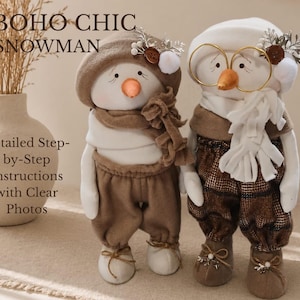 Pode incluir: Duas bonecas de boneco de neve feitas à mão. Uma usa boina e cachecol marrons, a outra óculos e cachecol branco. Ambas têm narizes laranja e estão vestidas com roupas marrons. O texto "BOHO CHIC SNOWMAN" é visível.