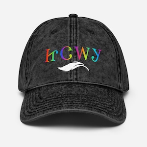 Op de afbeelding: Een zwarte, verwassen baseballpet met een gebogen klep. De pet toont het woord "HCWY" in regenboogkleurige letters boven een wit veermotief. De pet heeft een vintage, versleten uitstraling.