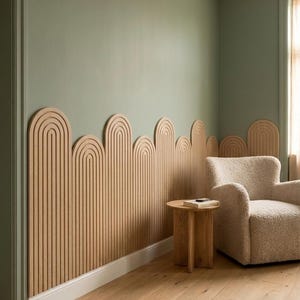 Può includere: Un pannello a parete in legno chiaro con un design ad archi ripetuti e listelli verticali. Il pannello è installato lungo la parte inferiore di una parete verde salvia, creando un bordo superiore smerlato che segue la forma curva degli archi.
