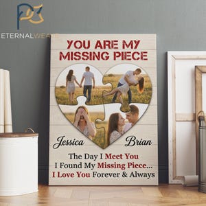 May include: A wooden wall art piece with a heart-shaped puzzle design. The puzzle contains four photos of a couple. Text reads "YOU ARE MY MISSING PIECE", "Jessica", "Brian", and a romantic quote. The background is a light wood grain.