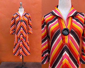 May include: A vintage 1970s dress with a colorful striped pattern in shades of pink, orange, yellow, and black. The dress has a collared neckline, long sleeves, and a button closure.