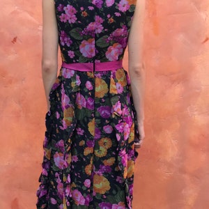 May include: A long black maxi dress with a pink floral print and a pink sash. The dress has a ruffled skirt and a sleeveless bodice.