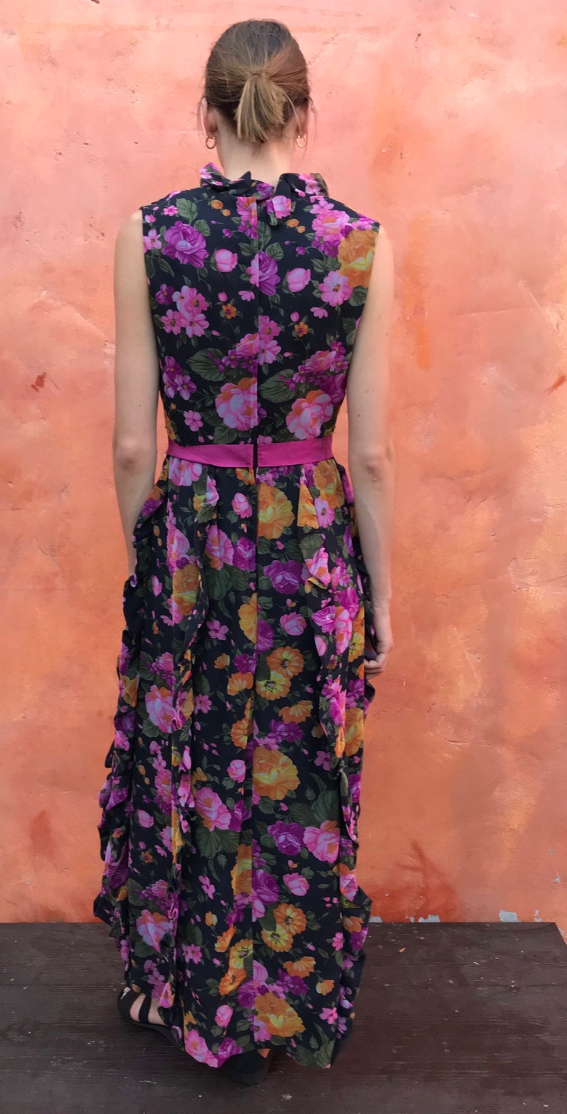 May include: A long black maxi dress with a pink floral print and a pink sash. The dress has a ruffled skirt and a sleeveless bodice.