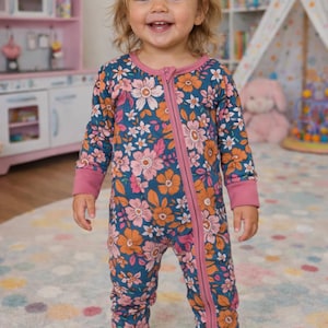 Puede incluir: Mono de bebé con estampado floral en azul marino, rosa y naranja. La prenda de una pieza tiene una cremallera completa, mangas largas y puños acanalados. El mono está adornado con un estampado floral y está diseñado para la comodidad y el estilo.
