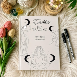 Könnte beinhalten: Ein weißes, rechteckiges Buchcover mit dem Titel Goddess INK TRACING PDF digital download, das schwarze Strichzeichnungen von drei Figuren mit langem Haar und Mondsicheln zeigt, begleitet von zwei schwarzen Stiften auf der rechten Seite.