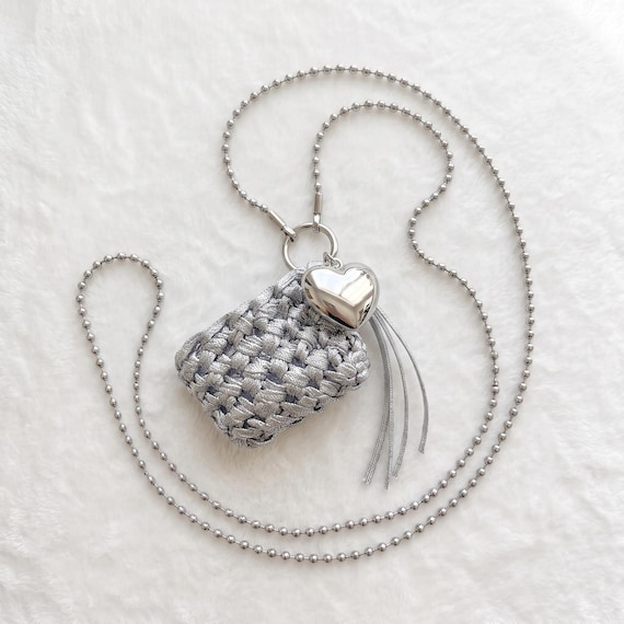 A hand-knitted silver lanyard pouch with a Y2K heart charm — wearable, functional, and genuinely quirky in a way you won't find at any chain store.