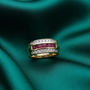 May include: A gold ring with a band of square-cut rubies and a row of small diamonds above and below the rubies. The ring is set against a dark green, silky background.