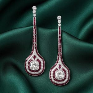 Könnte beinhalten: Ein Paar elegante Ohrhänger mit einem quadratisch geschliffenen Diamanten in der Mitte, umgeben von einem Kranz aus kleineren Diamanten und Rubinen. Die Ohrringe haben ein langes, schlankes Design mit Rubinen und Diamanten.