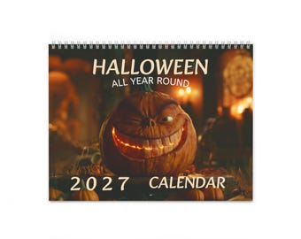 May include: A 2027 wall calendar with a spiral binding at the top. The cover features a large, glowing, carved orange pumpkin with a wide, toothy grin and a winking eye. The text reads HALLOWEEN ALL YEAR ROUND and 2027 CALENDAR.