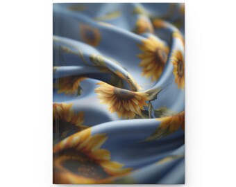 May include: A hardcover journal featuring a smooth, light blue fabric cover with a repeating pattern of yellow sunflowers. The surface of the cover is depicted with soft, flowing folds and ripples that create a dynamic, three-dimensional appearance.