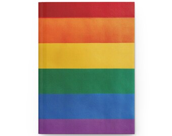 May include: A hardcover notebook with a rainbow flag design. The cover features horizontal stripes in red, orange, yellow, green, blue, and purple. The notebook is rectangular and appears to be made of a textured material.