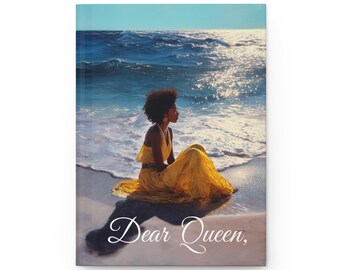 May include: A hardcover journal featuring an artistic illustration of a person in a yellow dress sitting on a beach, with the ocean in the background. The journal cover has the text "Dear Queen," in elegant script.
