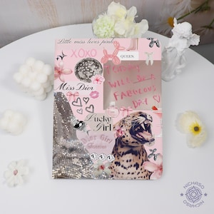 Könnte beinhalten: Ein rosa-silbernes Collage-Notizbuch mit Text und Grafiken. Das Notizbuch enthält die Sätze "Little miss loves pink", "Miss Dior" und "Lucky Girl". Weitere Grafiken sind eine Discokugel, Herzen und ein Leopard.