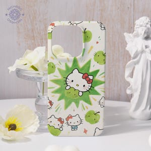Puede incluir: Funda de tel&eacute;fono blanca con un dise&ntilde;o de Hello Kitty, manzanas verdes y un fondo verde en forma de explosi&oacute;n. La funda tiene un patr&oacute;n repetido de Hello Kitty y manzanas. La marca "NICHASO" est&aacute; impresa en la esquina superior izquierda.