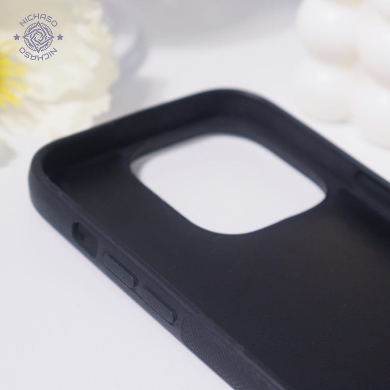 Puede incluir: Una funda de tel&eacute;fono negra con un recorte para la c&aacute;mara y detalles de botones. La funda tiene un acabado mate y un lateral texturizado. El logotipo "NICHAZO" es visible en la esquina superior izquierda.