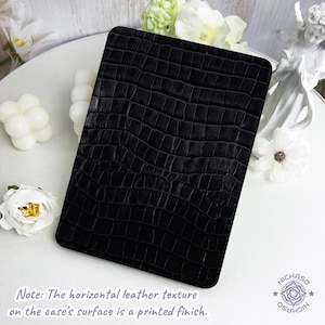 May include: A rectangular black case featuring a printed crocodile skin texture. The surface displays a repeating pattern of dark, embossed-style scales. The text at the bottom reads: Note: The horizontal leather texture on the case's surface is a printed finish.