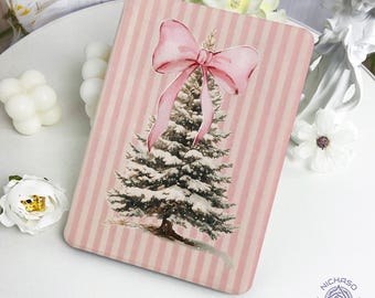 May include: A rectangular pink and white striped notebook featuring a watercolor illustration of a snow-covered Christmas tree and a pink bow. The notebook has a soft, pastel color palette and a festive theme.