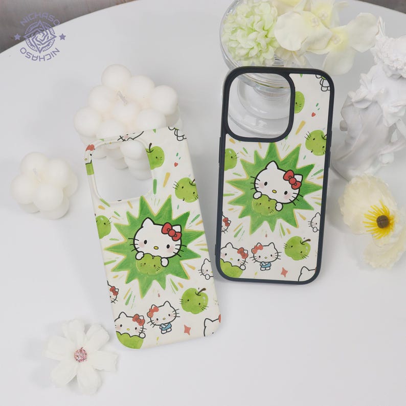 Puede incluir: Dos fundas blancas para tel&eacute;fono con un patr&oacute;n repetido de Hello Kitty, manzanas verdes y un dise&ntilde;o de estrella verde. Una funda est&aacute; plana y la otra est&aacute; en posici&oacute;n vertical. Las fundas tienen un borde negro.