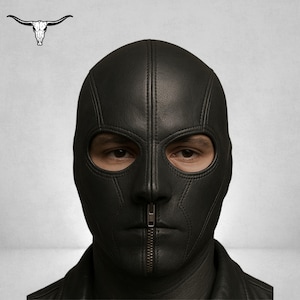 May include: Black leather balaclava with a full face design, featuring eye openings and a vertical zip closure. The mask is stitched and covers the entire head and neck. A bull skull logo is in the upper left corner.