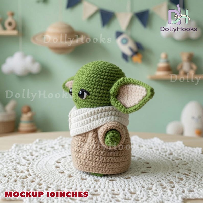 May include: A green crochet doll with large black eyes, pointed ears, and a white scarf, wearing a tan robe. The doll is positioned on a white circular lace doily. The text MOCKUP 10INCHES is printed in red at the bottom of the image.