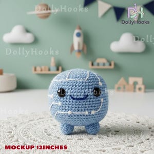 May include: A light blue crocheted plush toy shaped like a brain with white embroidered details. The toy has black button eyes and a smiling mouth. The text "MOCKUP 12 INCHES" is at the bottom. The background includes decorative elements like clouds and a rocket.