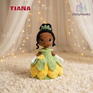 May include: A handmade crochet doll of a princess, featuring a green and yellow petal-shaped dress. The doll has black hair, a green crown, and white gloves. The doll is standing on a cream-colored surface. The text "TIANA Hooks" and "DollyHooks" are visible.