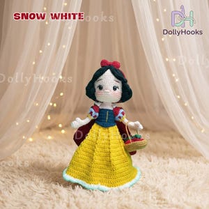 May include: A handmade crochet doll of Snow White, featuring a yellow dress, red bow, and a basket of red apples. The doll has black hair and a white face. The text "SNOW WHITE" is at the top of the image, with the DollyHooks logo on the right.