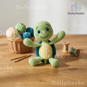 May include: A handmade green and yellow crochet turtle with blue accents, smiling, and with outstretched arms. A basket of yarn, crochet hooks, and spools of thread are in the background. The DollyHooks logo is in the top right corner.