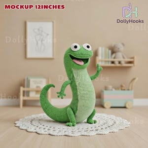 May include: A handmade green crochet lizard toy, approximately 30 cm tall, with a smiling expression and a pink tongue. The lizard is standing on a white doily. The background includes a shelf with books and a framed picture.
