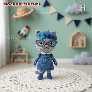 May include: A handmade crochet cat doll, approximately 12 inches tall, wearing a blue dress, beret, and glasses. The cat has gray fur and yellow eyes. The doll is standing on a white, circular rug.