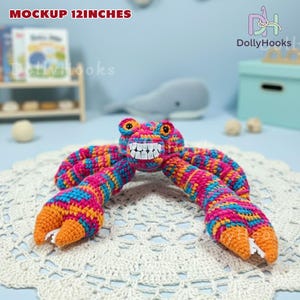K&ouml;nnte beinhalten: Ein geh&auml;keltes Krabbenspielzeug, etwa 30 cm lang, in leuchtenden Farben. Die Krabbe hat ein l&auml;chelndes Gesicht und gro&szlig;e Scheren. Das Garn ist rosa, blau, orange und gelb. Der Text "MOCKUP 12INCHES" ist oben sichtbar.