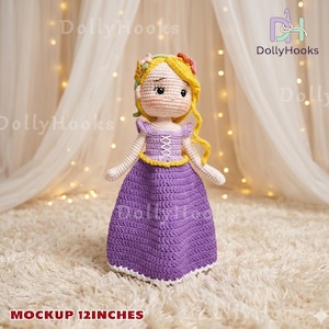 May include: A handmade crochet doll, approximately 12 inches tall, featuring a princess design. The doll has blonde hair, a purple dress, and a floral crown. The doll is standing on a white, fluffy surface. The text "Mockup 12 inches" is at the bottom.