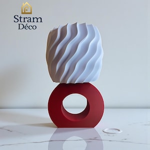 Puede incluir: Escultura decorativa moderna con una parte superior blanca ondulada y una base circular roja. Diseño minimalista, colocada sobre una superficie de mármol. El texto "Stram Déco" es visible. Ideal para la decoración de interiores.