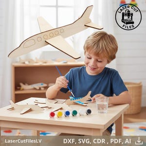 May include: A wooden airplane model kit with a child painting it. The kit includes several unpainted wooden airplanes, paint pots, and a paintbrush. The image also includes the text "LaserCutFilesLV" and "DXF, SVG, CDR, PDF, AI".