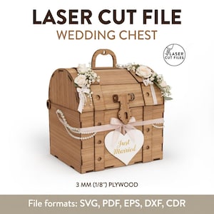 May include: A laser cut wooden wedding chest made from 3 mm (1/8 inch) plywood. The chest features a top handle, a latch, and decorative white floral accents. A white heart-shaped tag with the gold text Just Married hangs from a light pink ribbon.