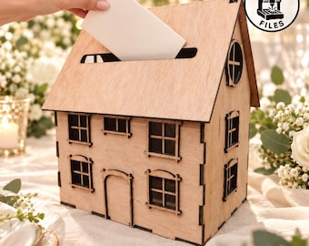 May include: A light-colored wooden house-shaped card box with a slot on the roof for inserting envelopes. The structure features laser-cut window and door details, a circular side window, and a circular logo in the corner reading LASER CUT FILES.