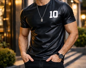 Op de afbeelding: Zwart shirt met korte mouwen en het nummer 10 in het wit op de borst. Het shirt wordt gecombineerd met een zwarte jeans en een zilveren ketting. De persoon draagt een zonnebril en een zwart horloge.