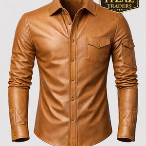 Op de afbeelding: Een bruin leren overhemd met een knoopsluiting, twee borstzakken en twee mouwzakken. Het overhemd heeft lange mouwen en een kraag. De afbeelding bevat een zwart en goud logo met de tekst "REAL LEATHER ITZAZ TRADERS."